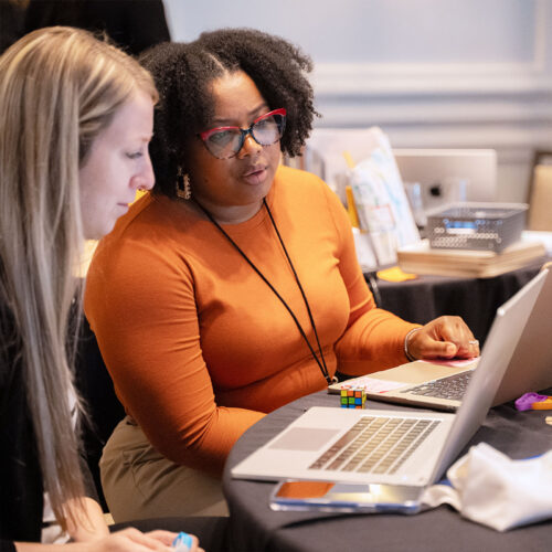 Two adults work together on their laptops