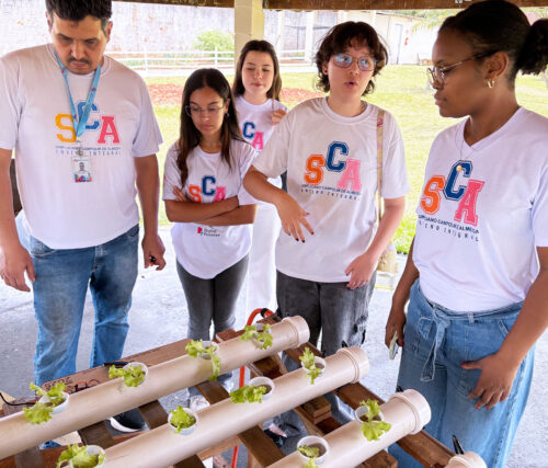 A group of students gather around plants outside