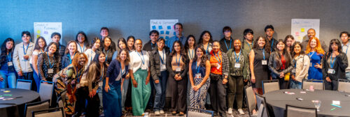 A group of about 50 people with name tags smiles for a group photo