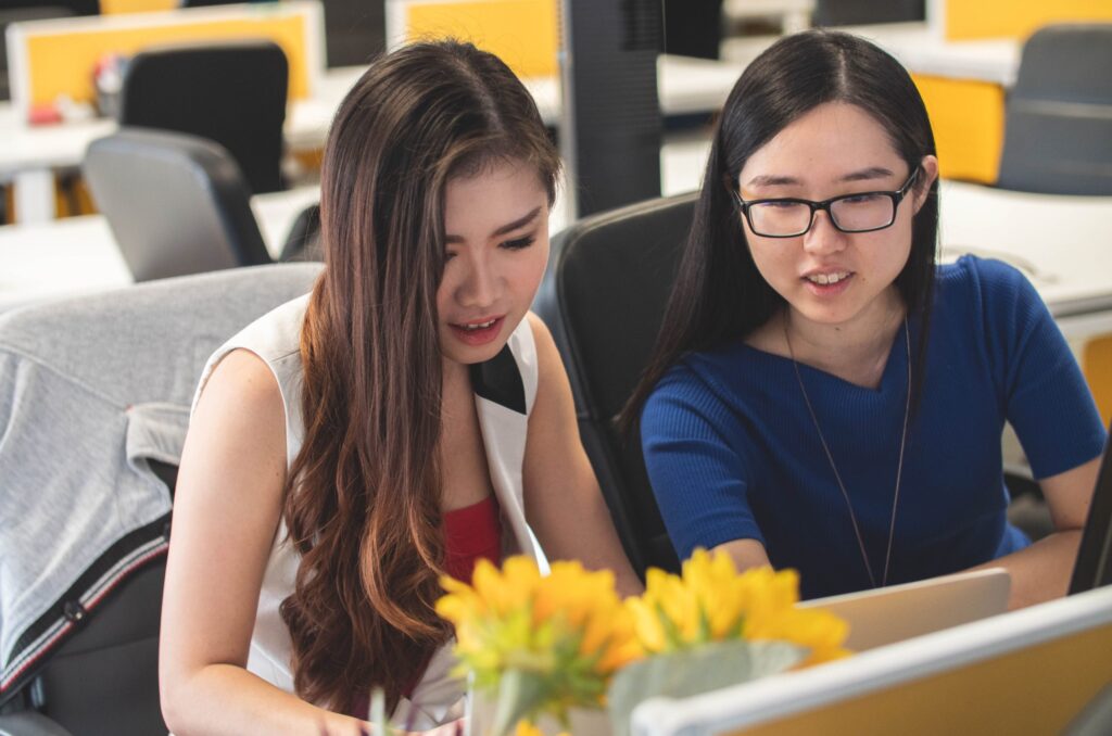 Two women working at a laptop.