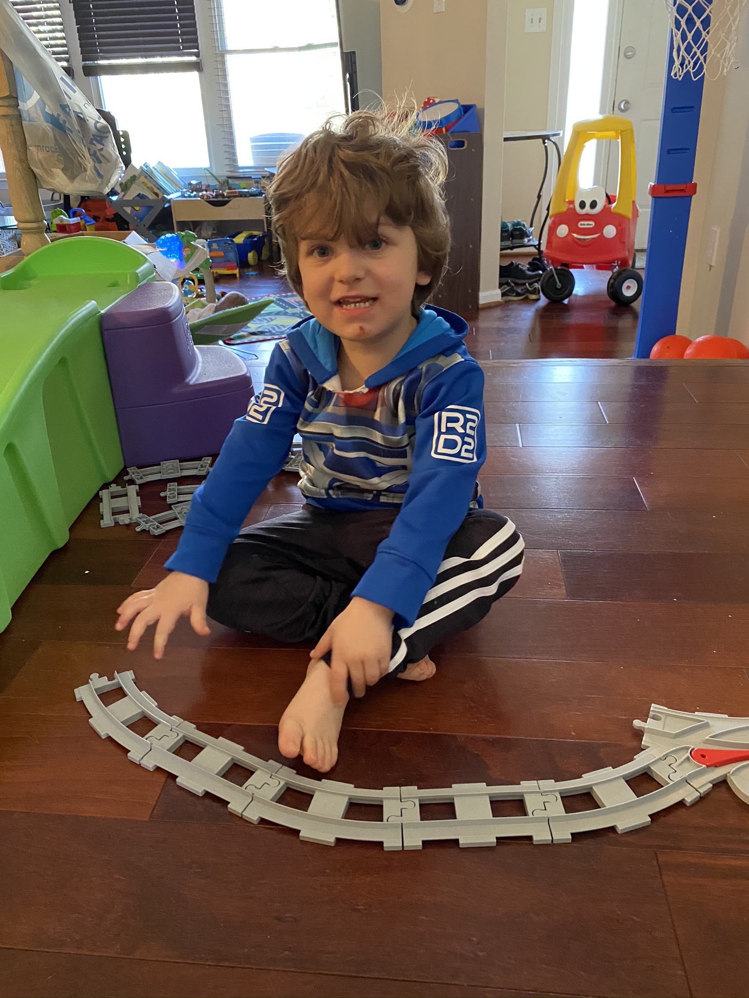 Young boy playing with toy train tracks