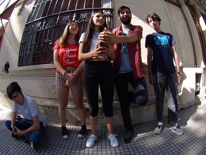 Three students and an educator standing on the street around a 360º camera.