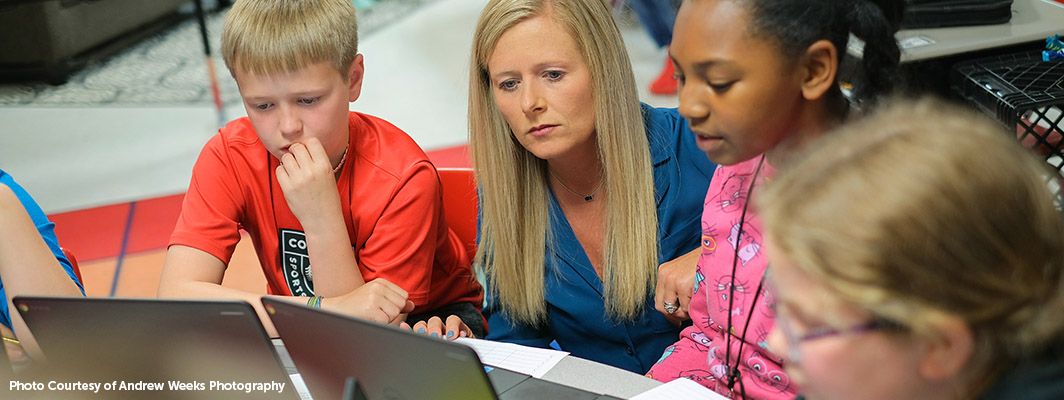 Students working on their laptops alongside their teacher