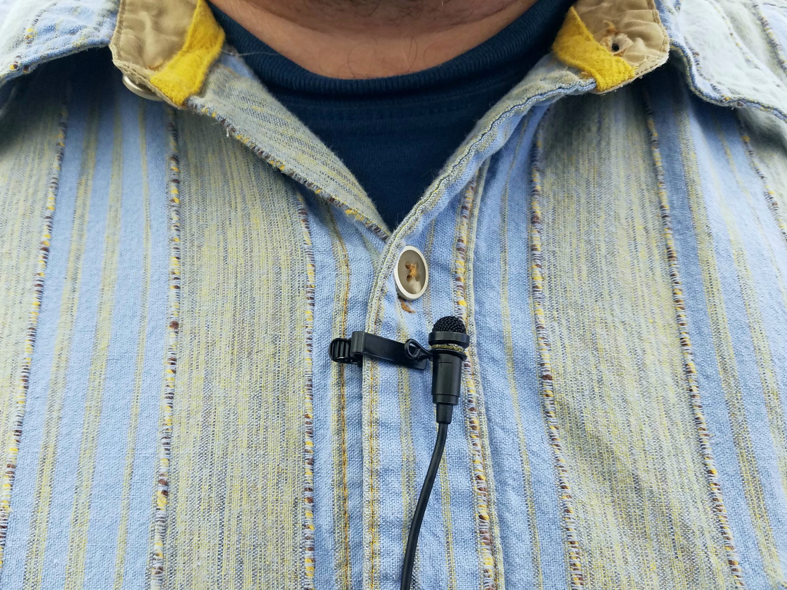 A small microphone pined to a man's lapel.