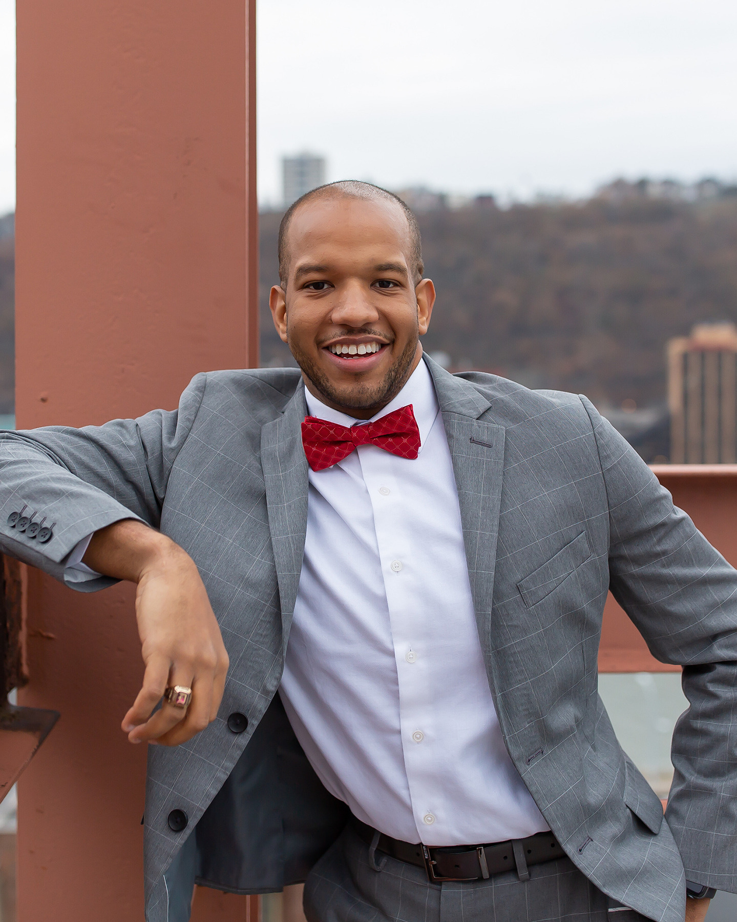Black man wearing grey suit with red bow tie in industrial setting