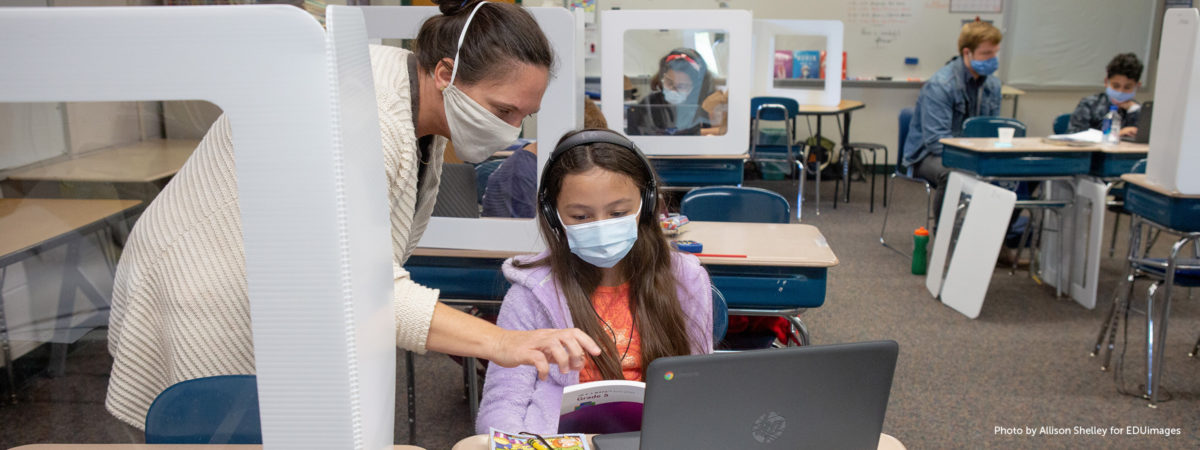 Female teacher and fifth-grade student with masks