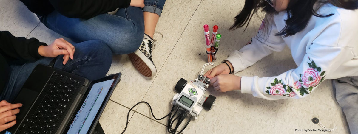 Photo of three students working on a robotics project