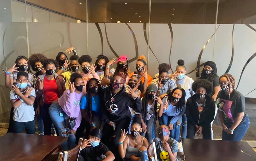 Glamorous Gemz youth participants with their facilitator. A group of young, Black participants. All are wearing Glamorous Gemz face masks.