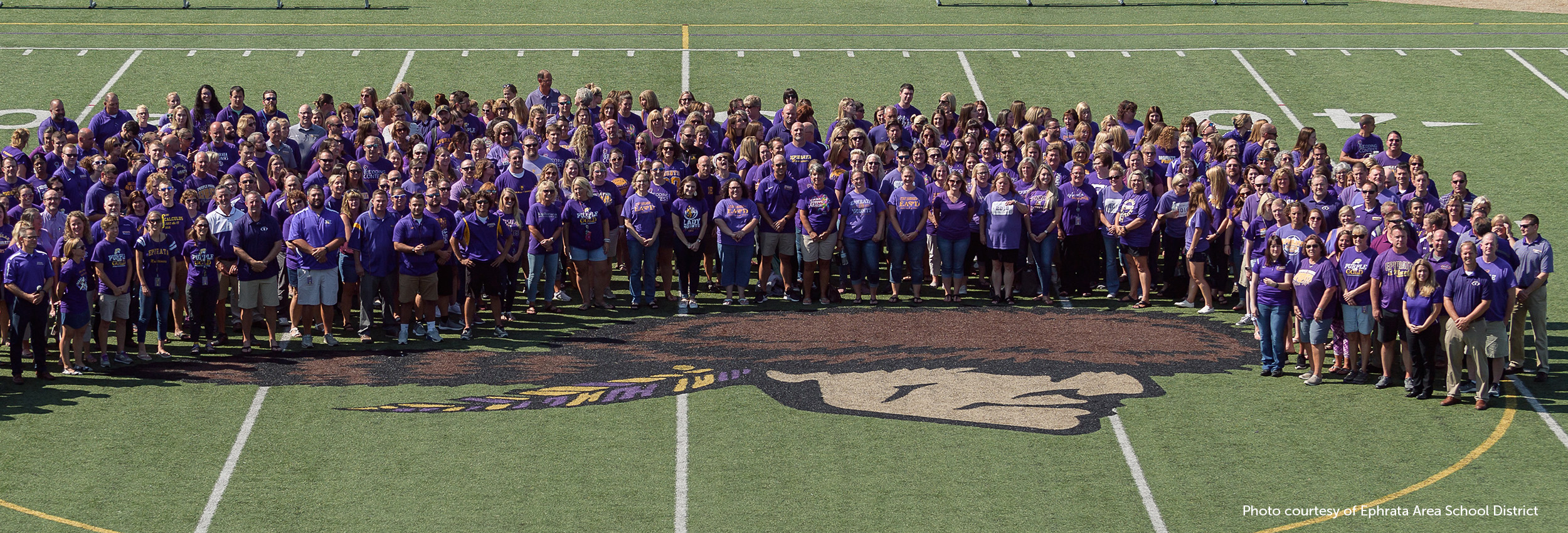 Ephrata Area School District Staff pose at the center of a football field