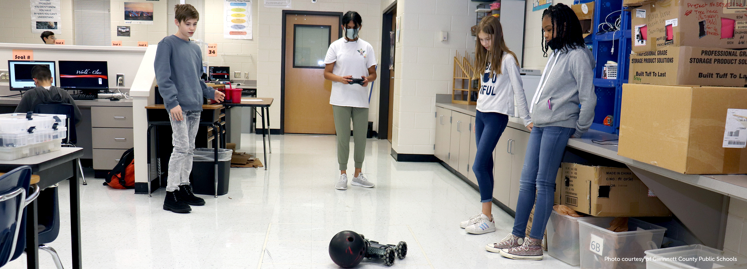 Three students from Gwinnett County Public Schools control a robot via remote control in order to move a bowling ball