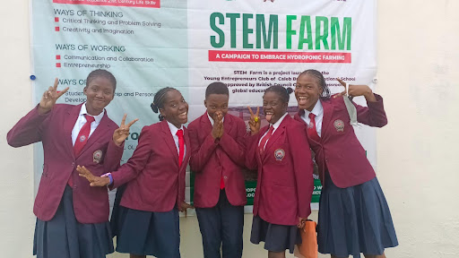 Five students standing in front of a STEM FARM banner.