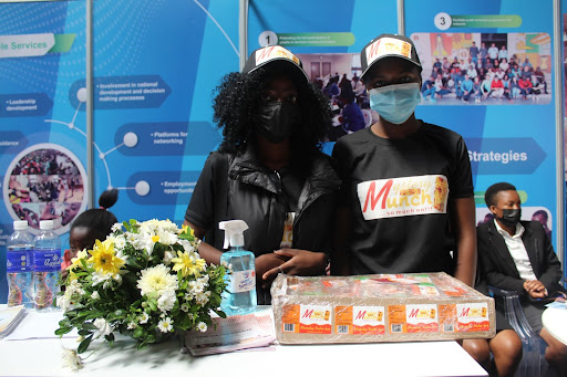 Two students pose with their snack bars at their table in a trade fair
