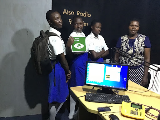Students pose with a climate action poster in the studio of a radio station