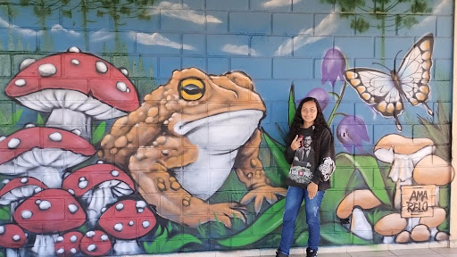 A student poses in front of a mural 