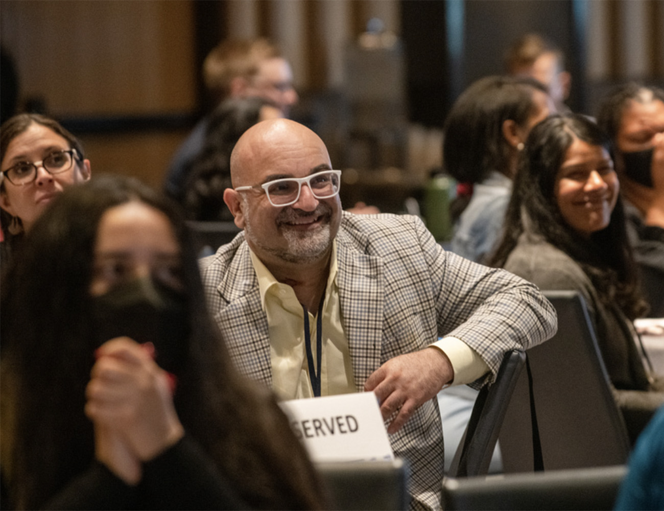 A man in a conference room smiles as he's watching a presentation at the Inclusive Innovation Convening in 2022
