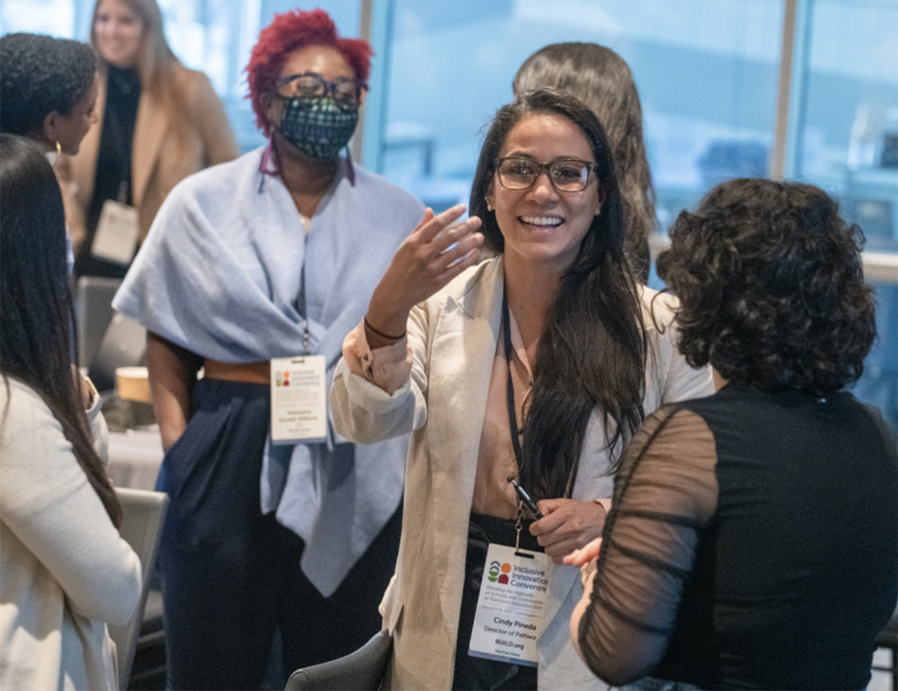 A woman at the Inclusive Innovation convening smiles and waves to someone out of frame