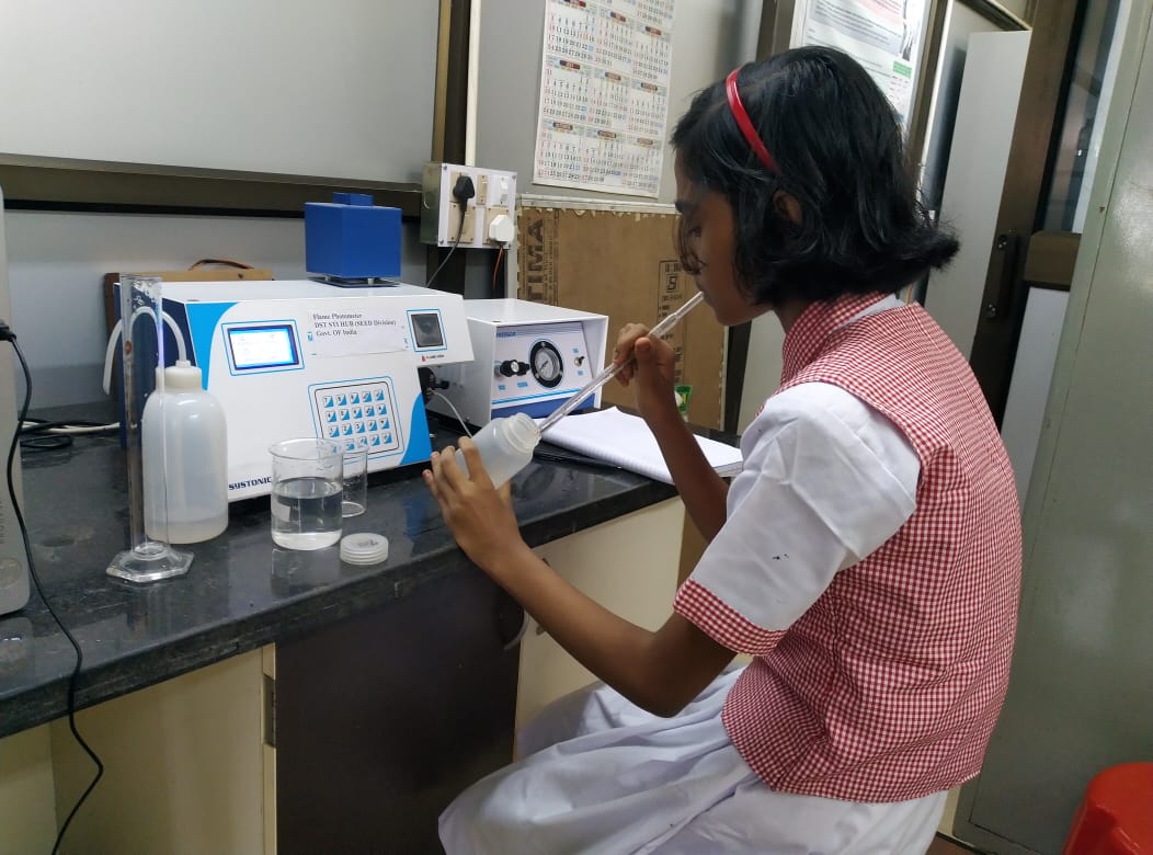 A Santamayee High School student sits at a desk and works with laboratory equipment at idho-Kanho-Birsha University.