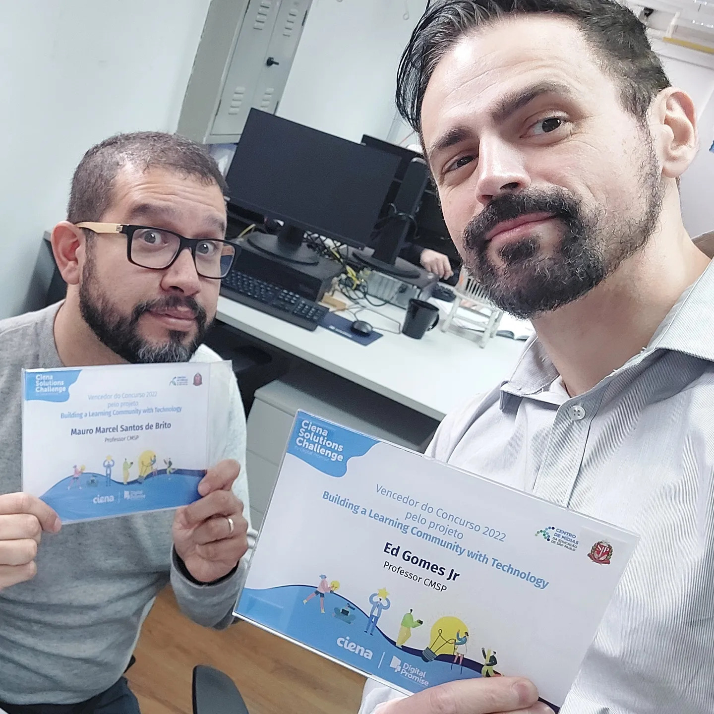 Teachers Mauro Marcel and Ed Gomes Jr. hold up their certificates in a selfie