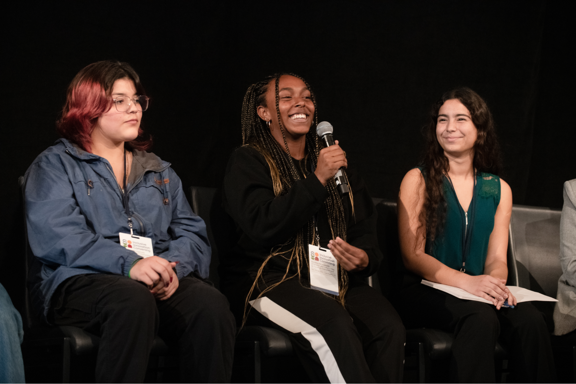 Three students speak on a panel on stage.