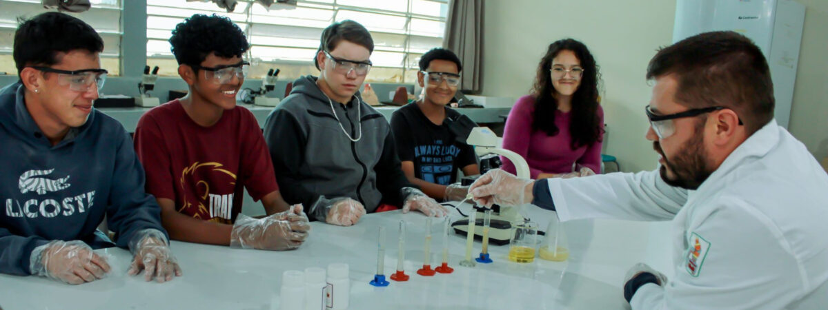 Students work with their teacher at a lab station