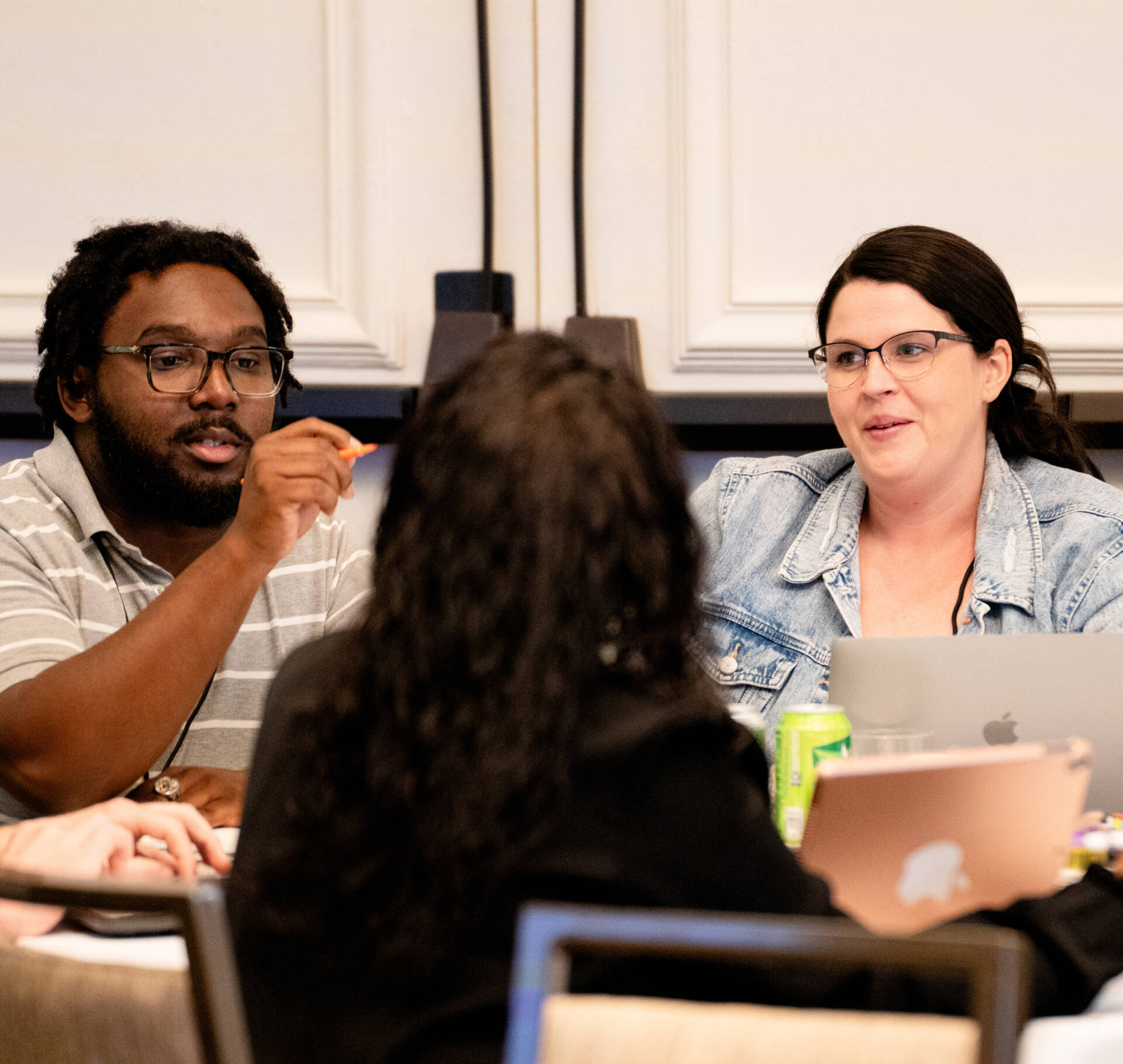 Three people talking in a classroom.