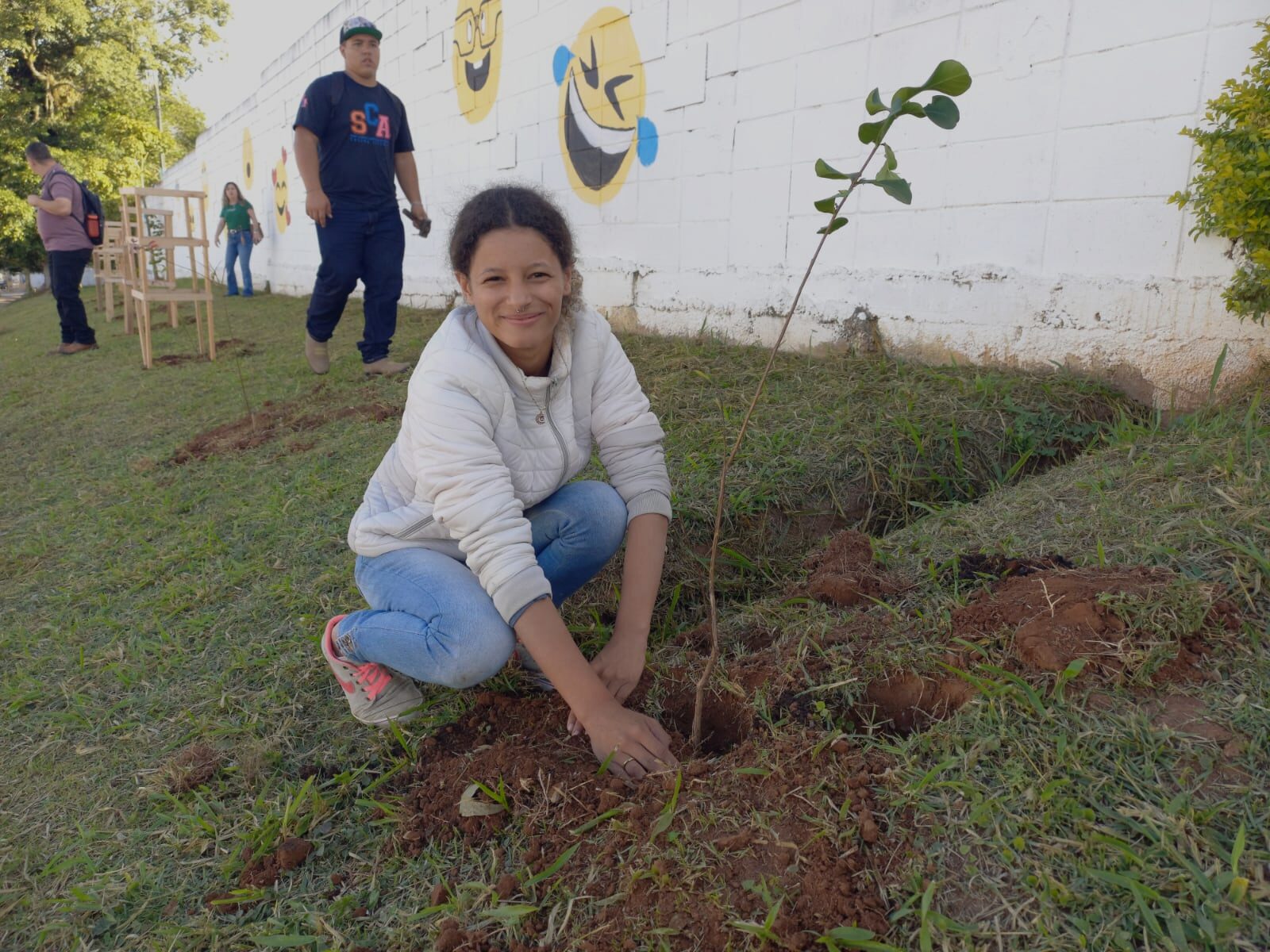 A student plants a plant into the ground. 