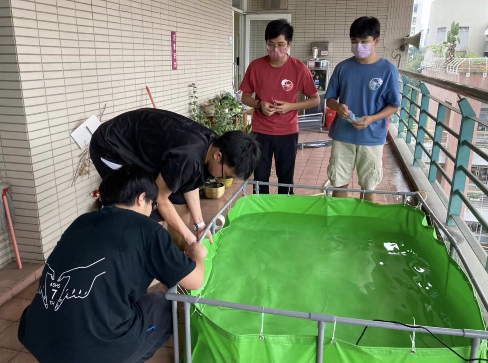 Three students work with a tank made of tarp. 