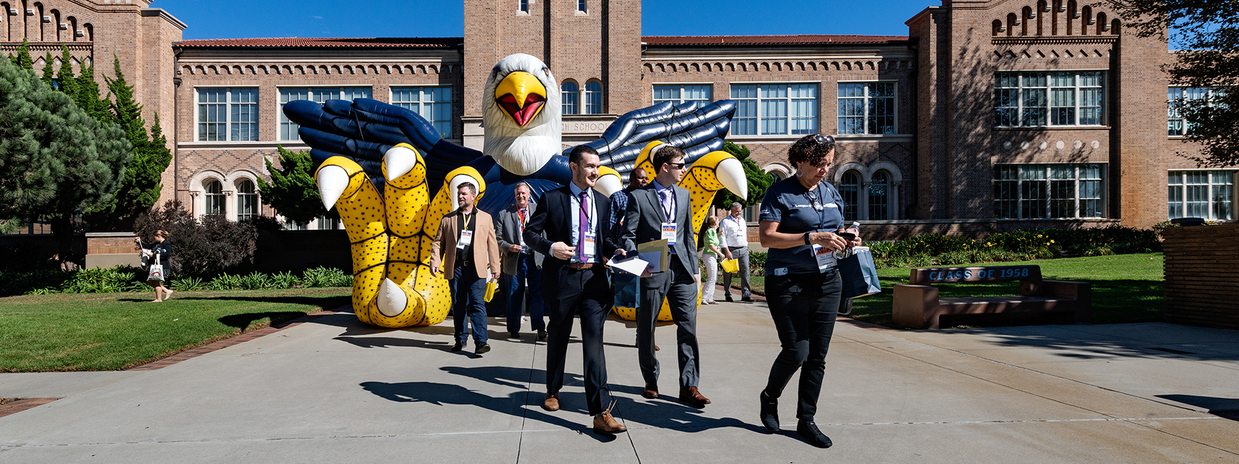 Photo of League Members walking away from a school building. Behind the League members is an inflatable of an eagle, the school's mascot.