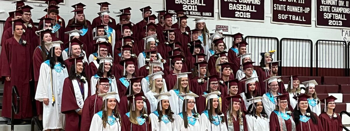 Rows of high school students in maroon and white graduation caps and gown