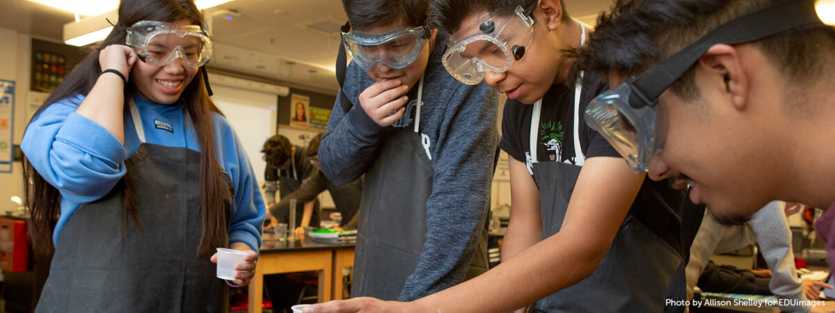 Three high school boys and one high school girl work together on an experiment in AP chemistry class.