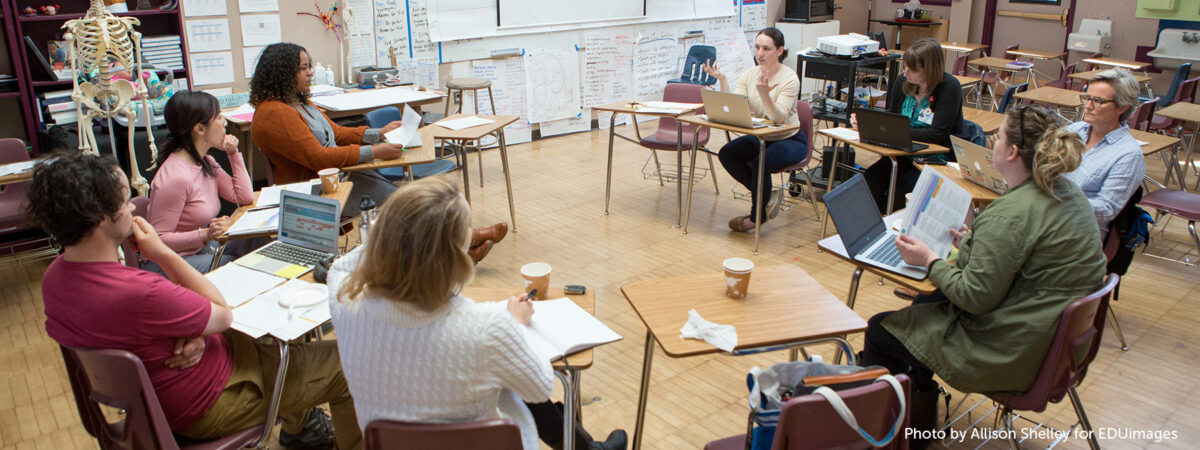 An image of teachers sitting around in a circle discussing.