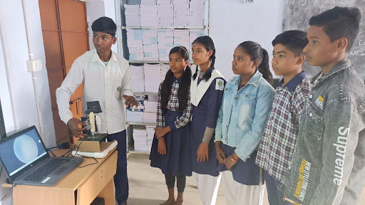 Six students stand and watch a screen projector. 