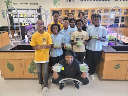 A chef poses with students and the vegetables they grew.