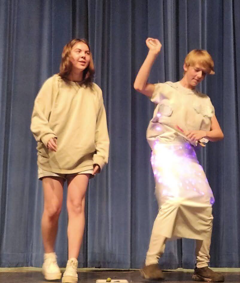 Two students stand on stage wearing their designs.