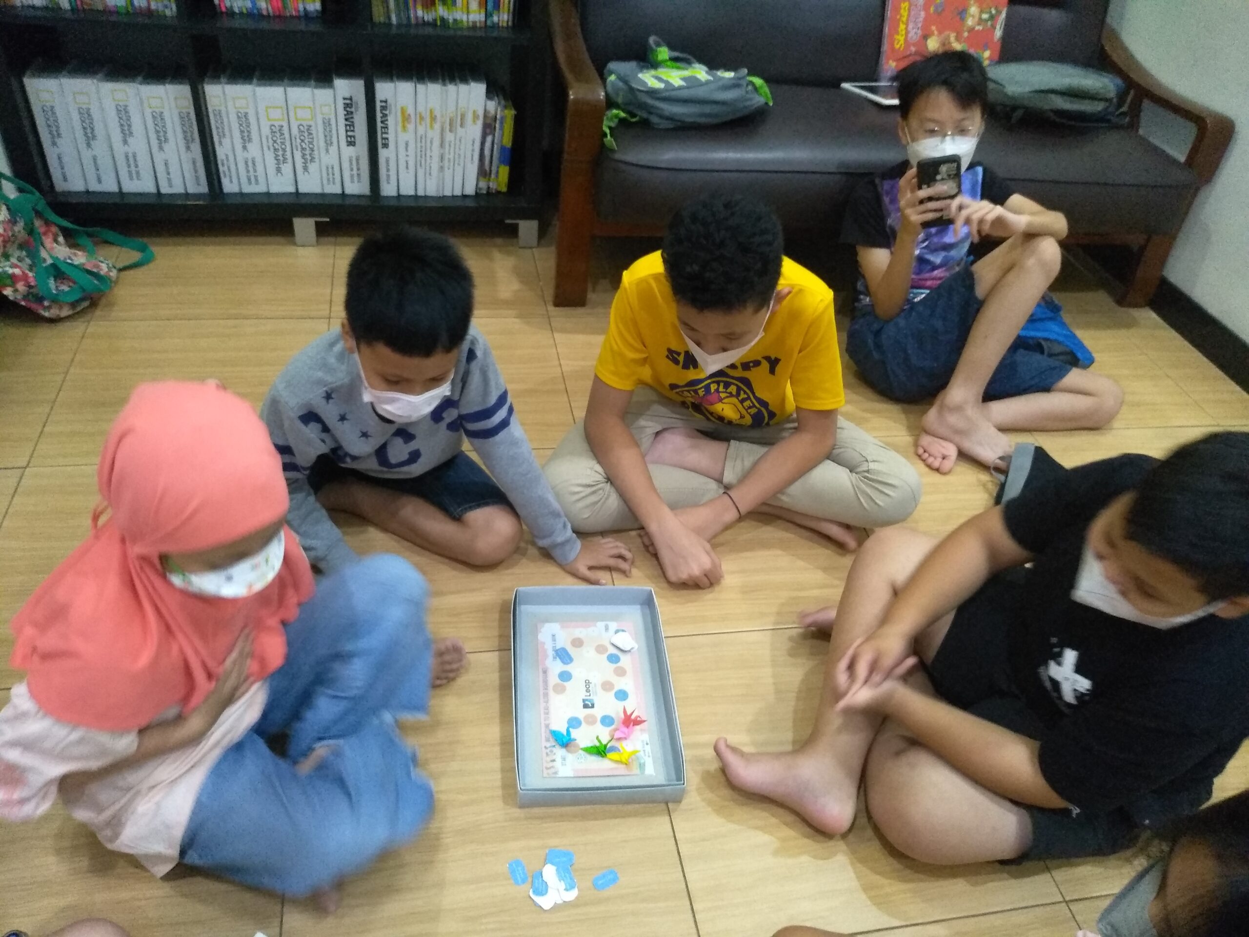 A group of students sit around a board game