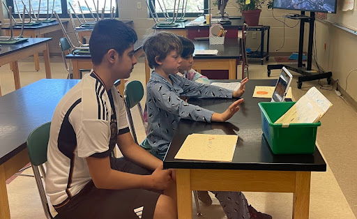 Three students present in front of a laptop. 