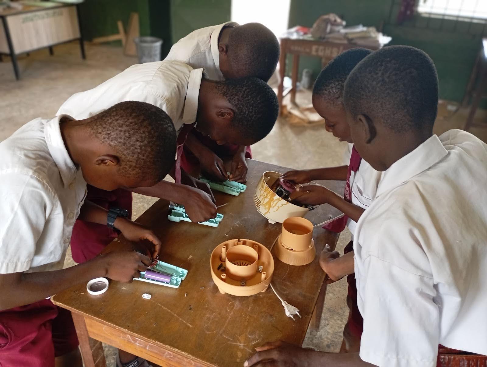 Five students stand around a desk tinkering on their prototypes 