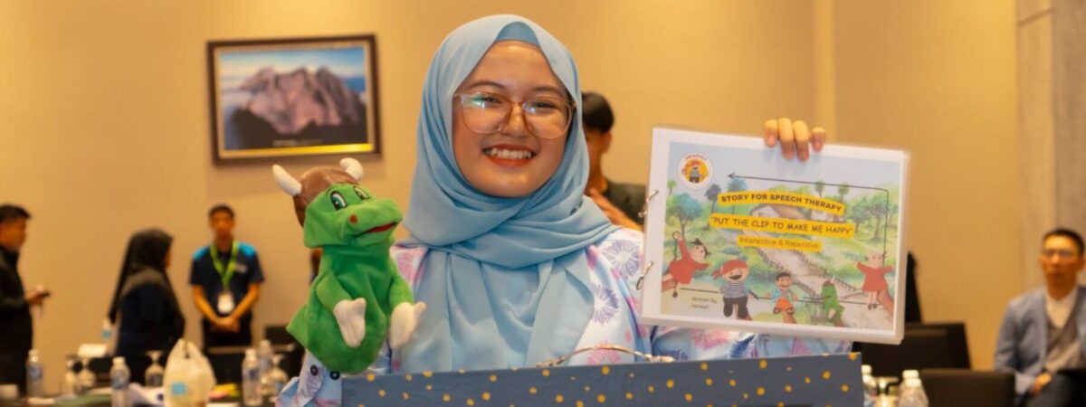 A student poses with a puppet, certificate, and a painting.