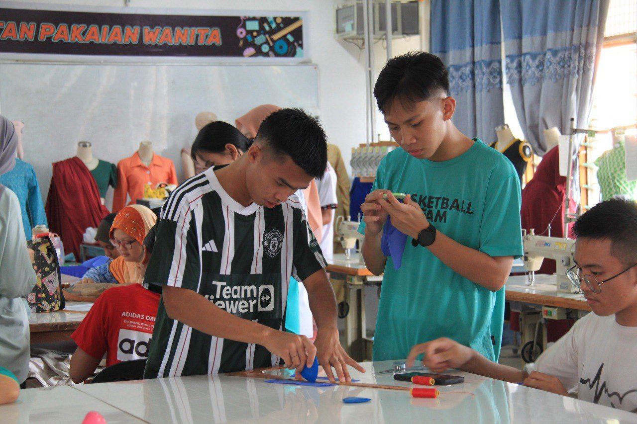 Two students measure materials in the sewing and design workshop. 