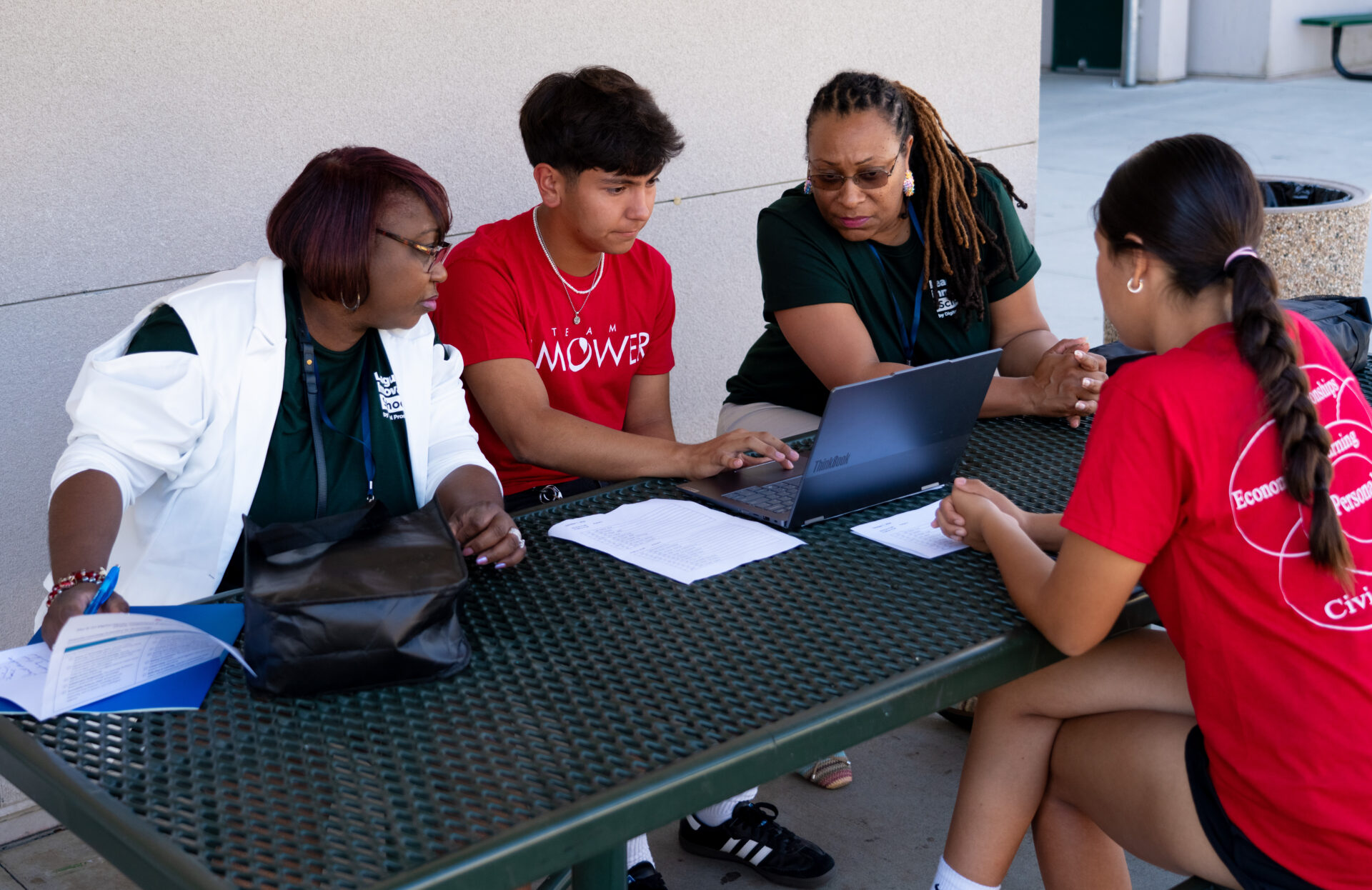 image of one male and one female student showing two female adults something on a laptop 