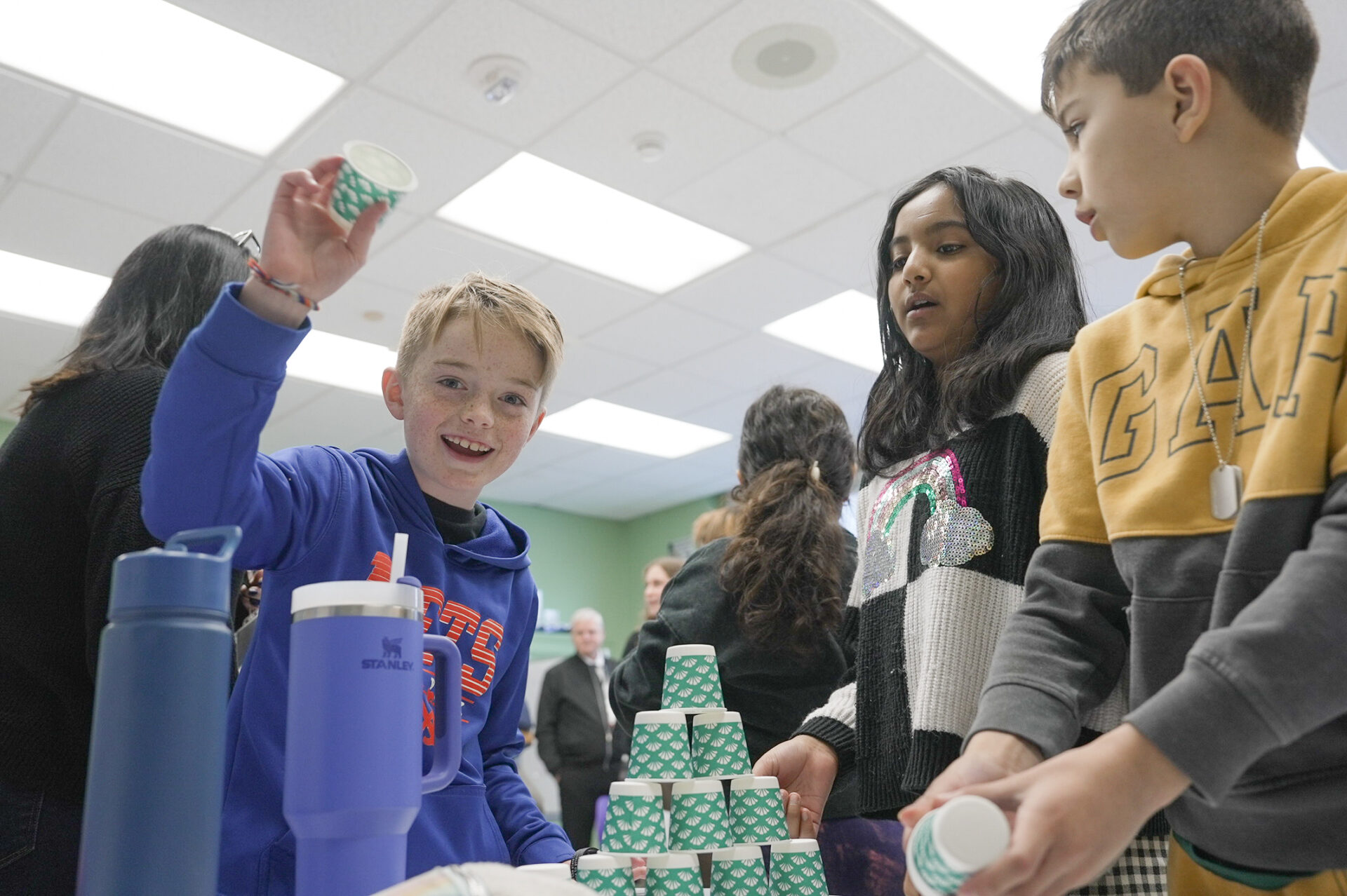 Photo of three children at a desk stacking a pyramid of cups 