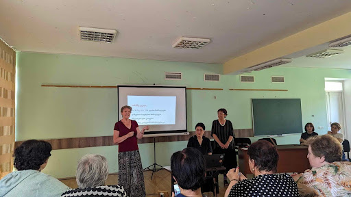 Three teachers present in front of a group of their colleagues. 