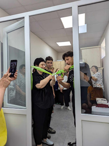 Students and teachers celebrate as one student cuts a ribbon in the doorway of the "study pod" room. 