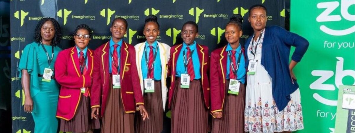 Students and their teacher line up in front of a step-and-repeat at a convention