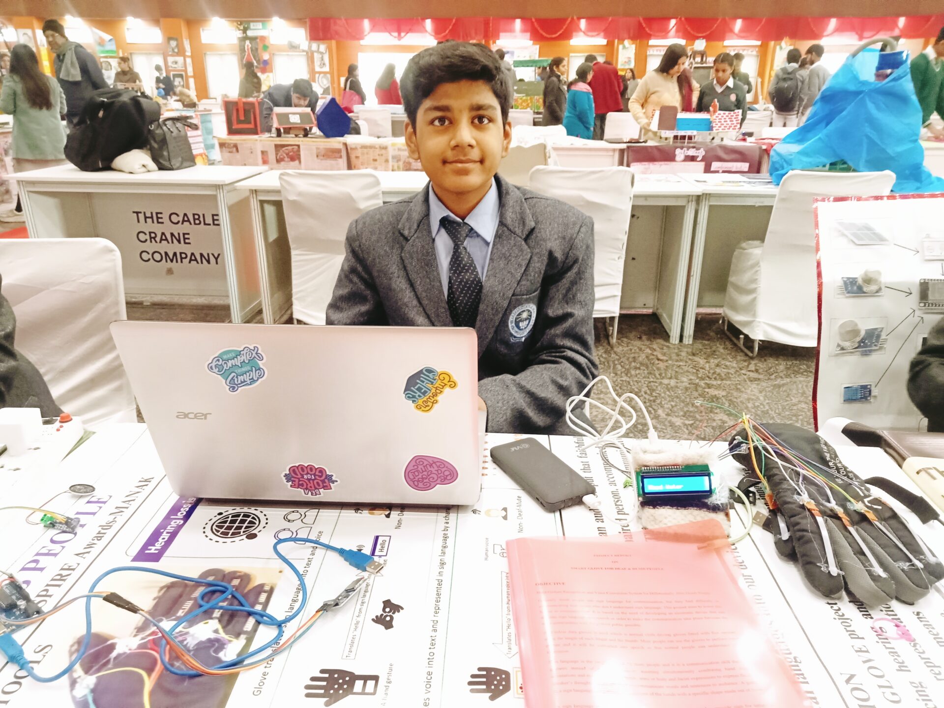 Divit looks up while seated at an expo table with his laptop, data gloves, and other devices 