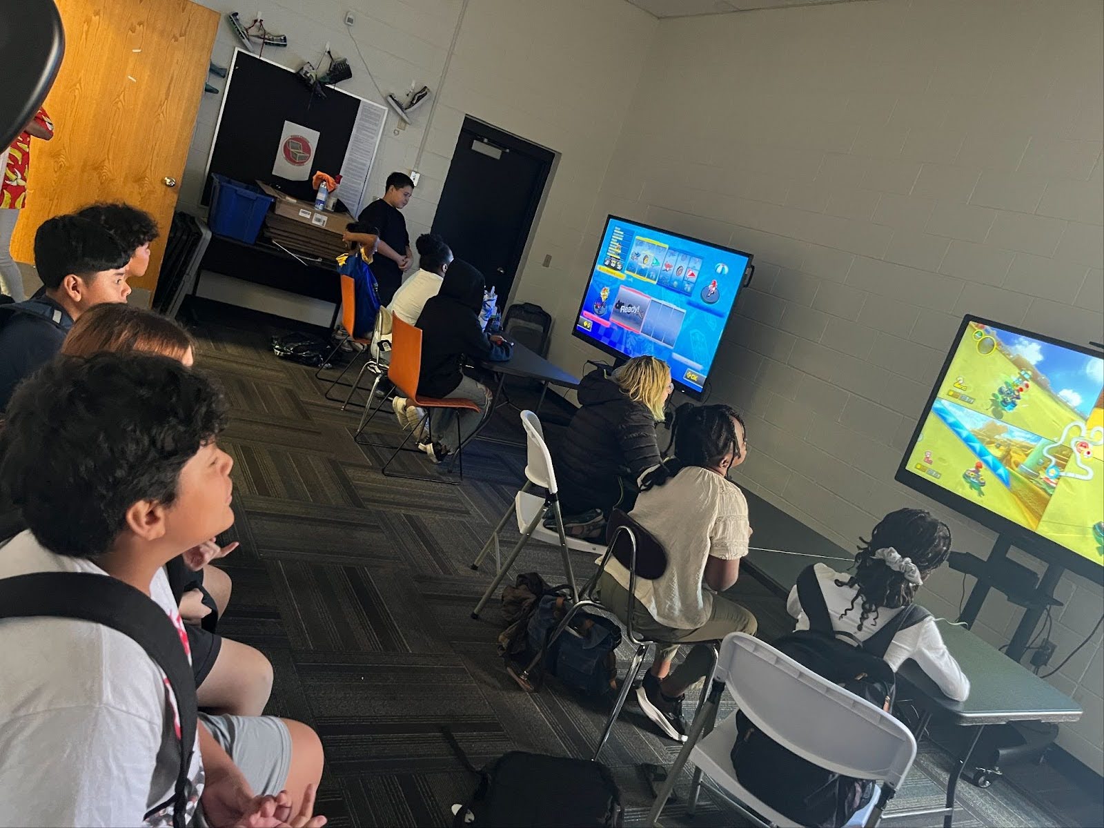 Students are seated in front of computer monitors while playing a game.