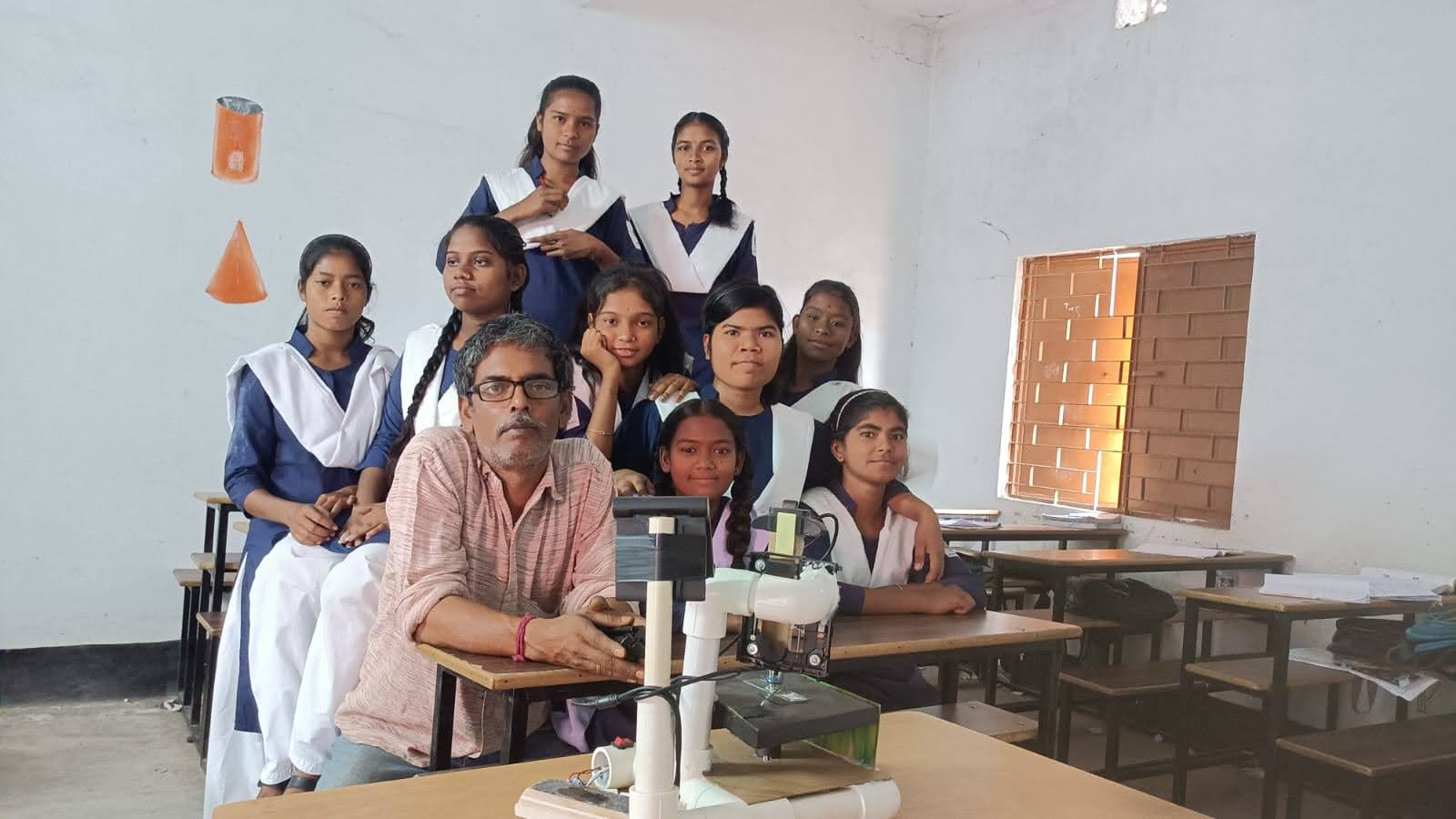 Students and their teacher pose for a photo inside a classroom. 