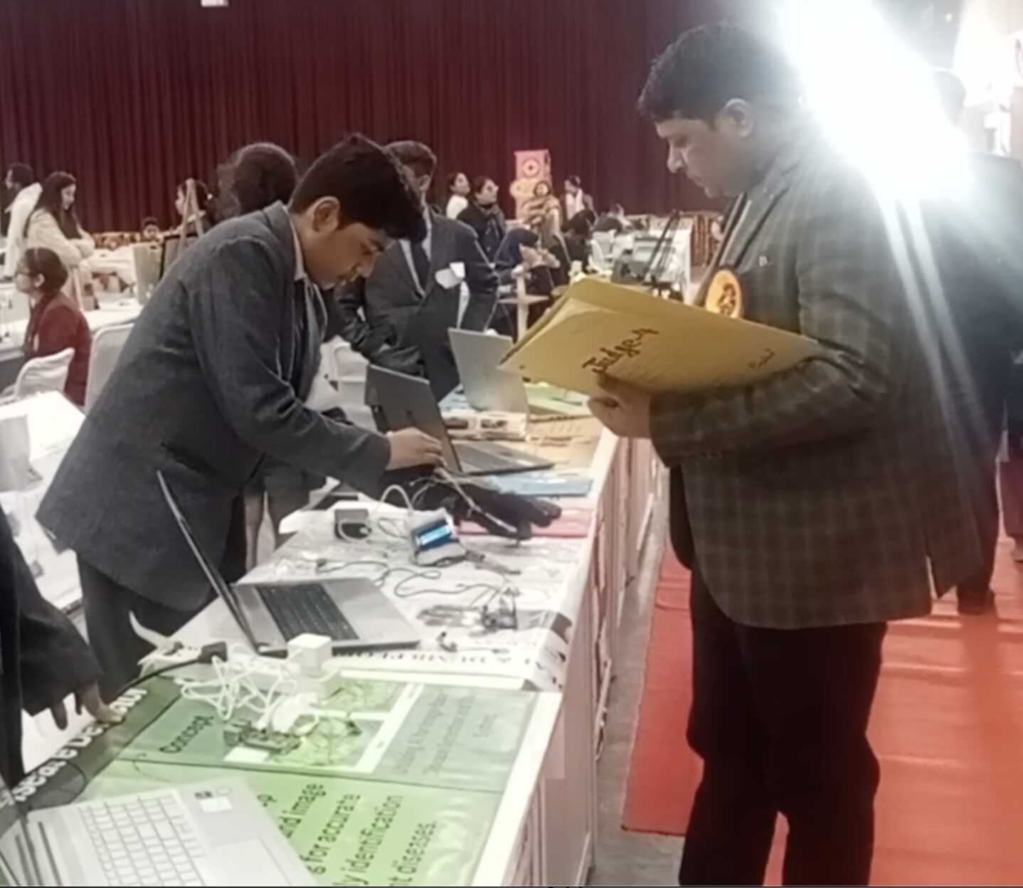 Divit wears a data glove as he demonstrates his project to an adult visiting his table at an exhibition 