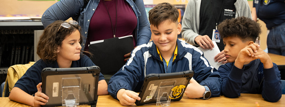 Three students are looking at two ipads