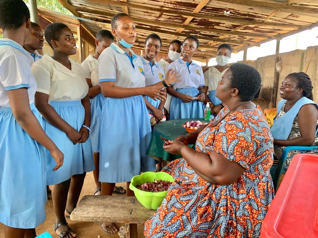 A group of students speak to two women in their community.